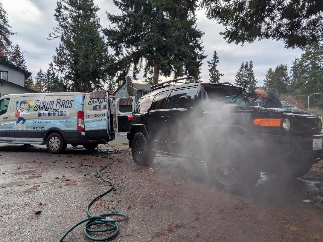 Scrub Bros van on-site with team pressure washing a truck